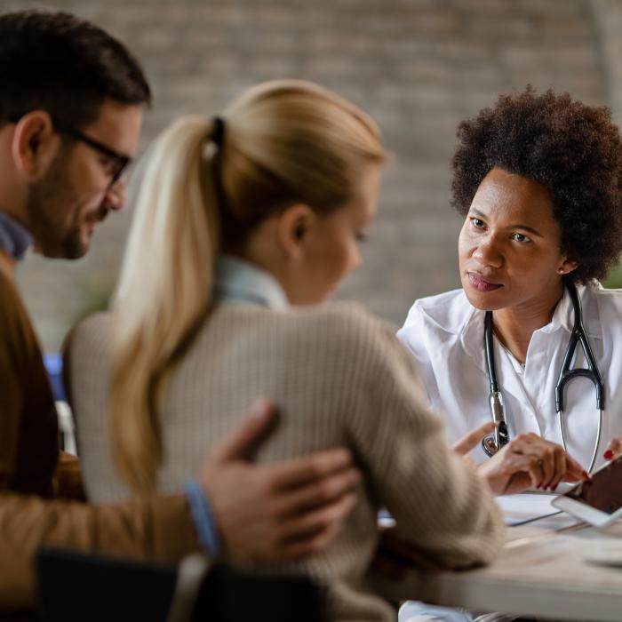 Doctor sitting at her desk and talking to a couple