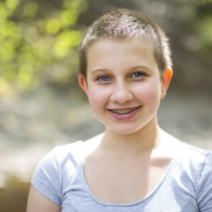 Image of a young adult wearing a short sleeve t-shirt, with short hair, and smiling. 